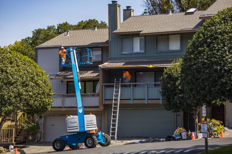 Two men painting the outside of a house